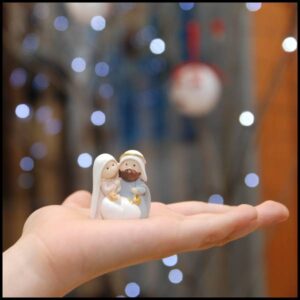 Mary, Joseph and baby Jesus ornament in the palm of a hand.